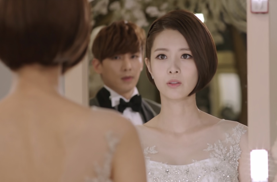 Tae Yi-ryung de noiva e o noivo olhando para uma mulher de costas no salão do casamento