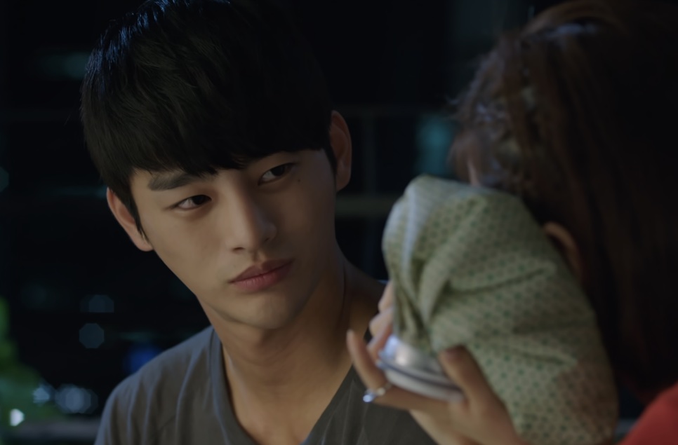 Close de Kang Woo à noite, olhando para Tae Yi-ryung, que está de costas em primeiro plano