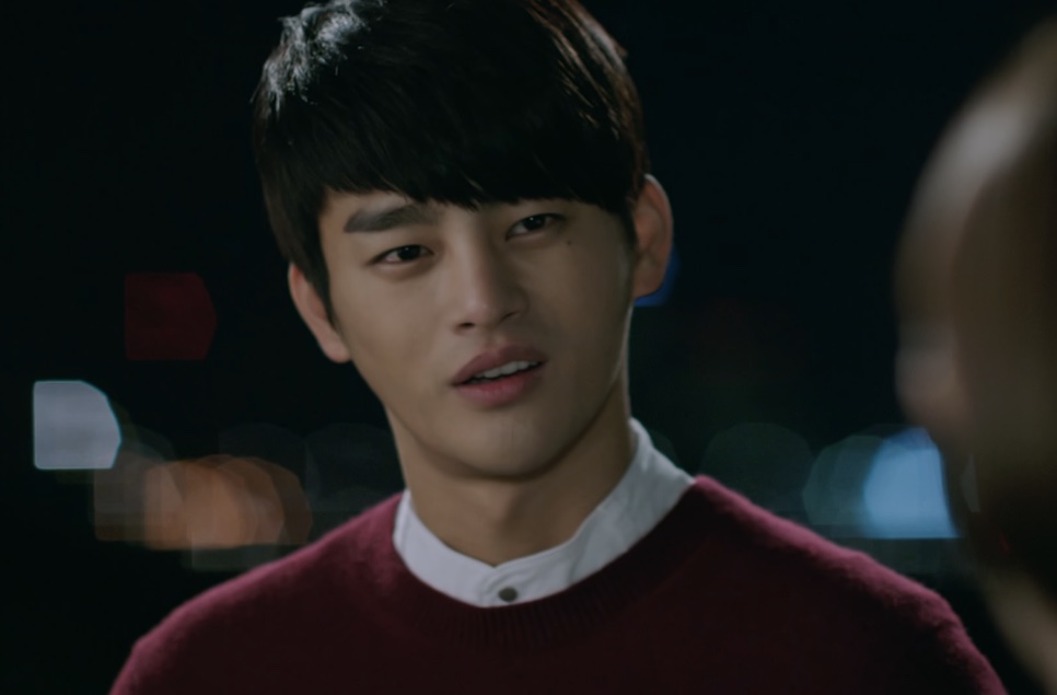 Kang Woo de suéter vinho falando com alguém em uma rua escura