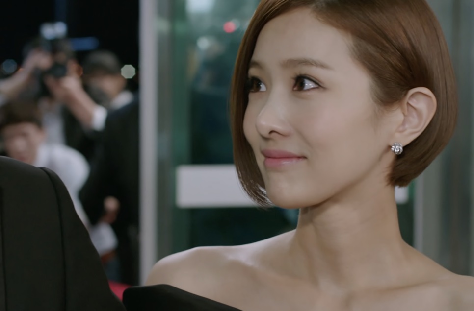 Tae Yi-ryung sorrindo no tapete vermelho, com fotógrafos ao fundo