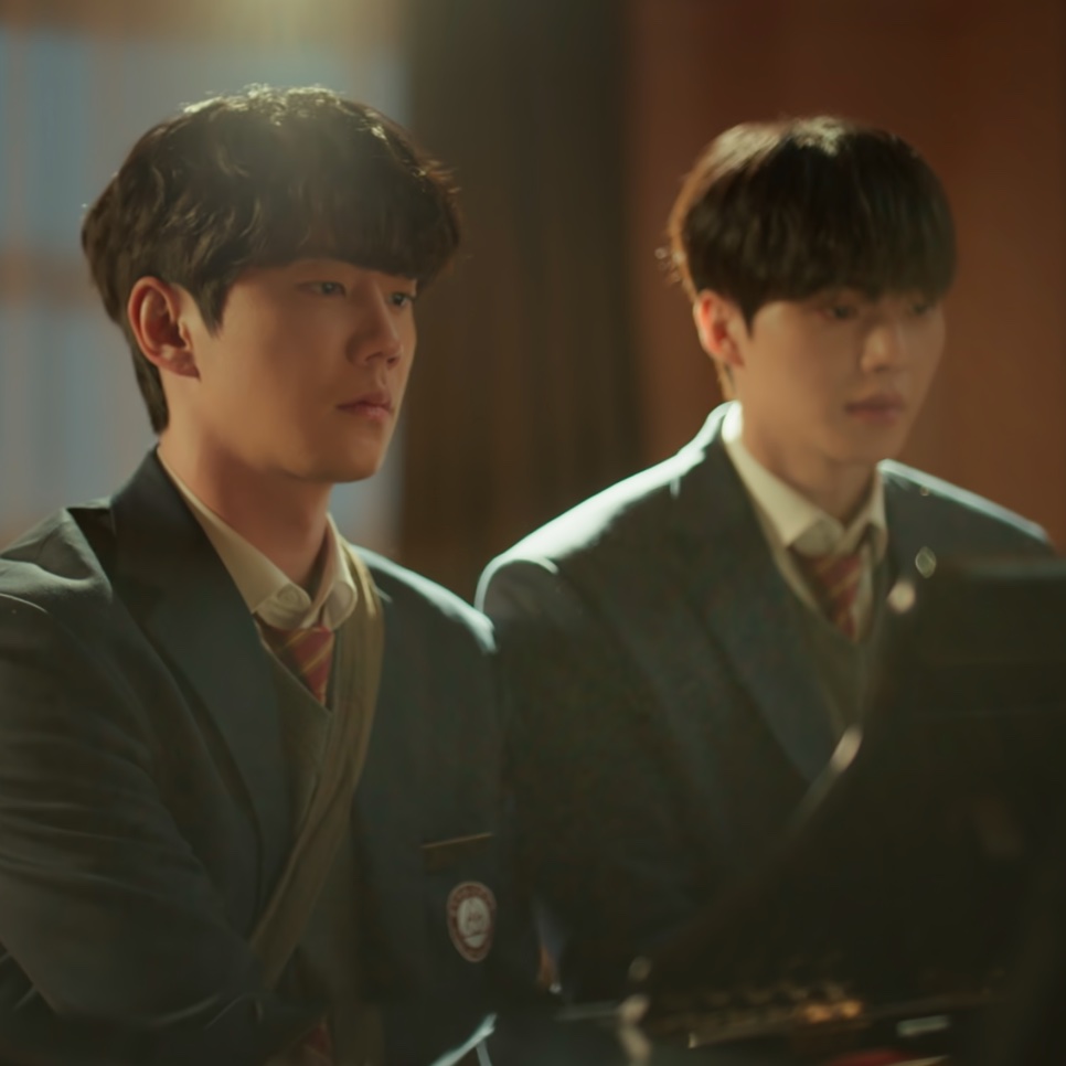 Kang Pi-o (Song Kang) e Choi Jeong-yo (Lee Jun-young), de uniforme escolar, lado a lado ao piano em Quatro Mãos, Duas Sonatas