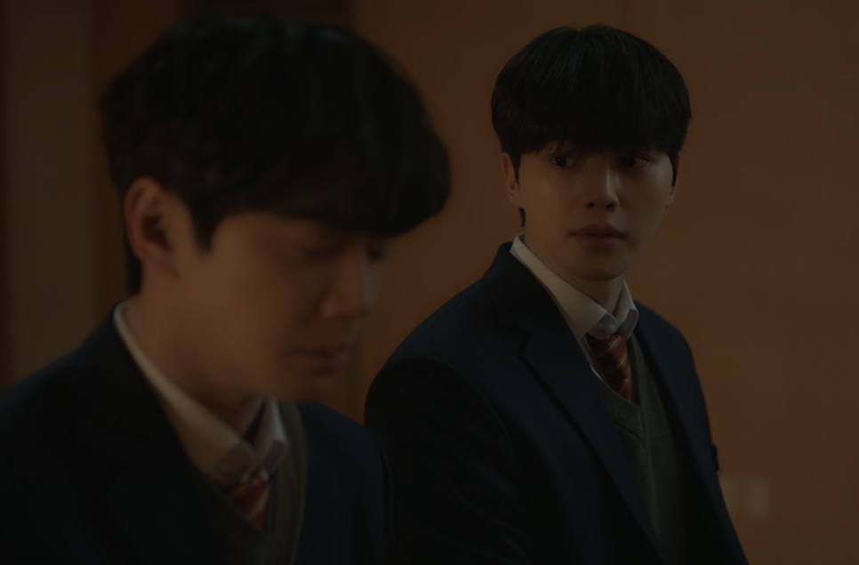 Os dois protagonistas de Quatro Mãos, Duas Sonatas, de uniforme escolar, numa sala com pouca luz