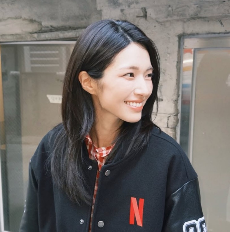 Ha Young de jaqueta preta, sorrindo
