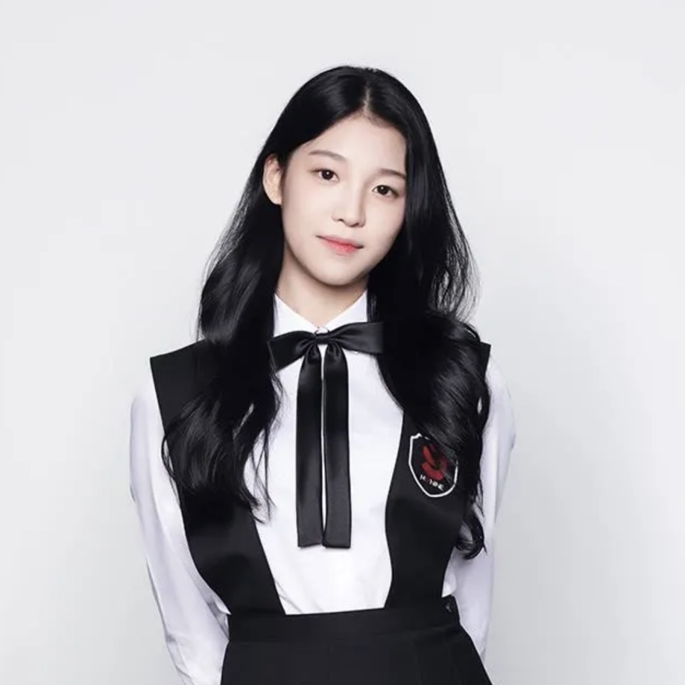 Baek Hyun-joo, hoje a atriz Baek Yae-in, de camisa branca e colete preto com laço, na foto de perfil do Mix Nine