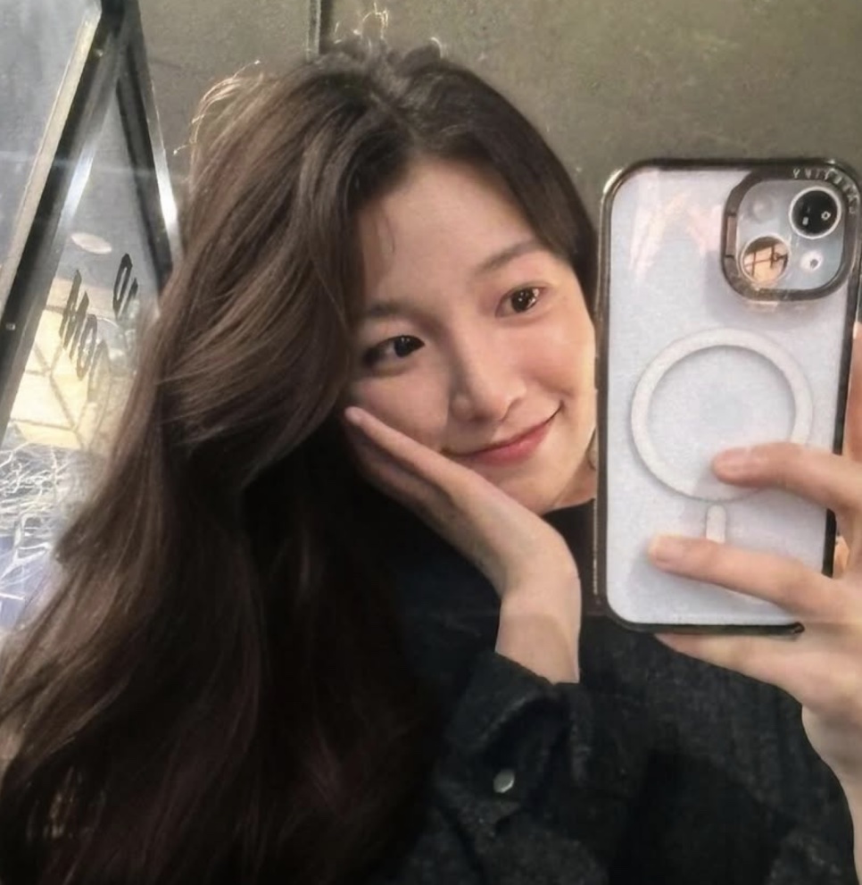 A atriz Baek Yae-in tirando selfie no espelho com a mão no rosto