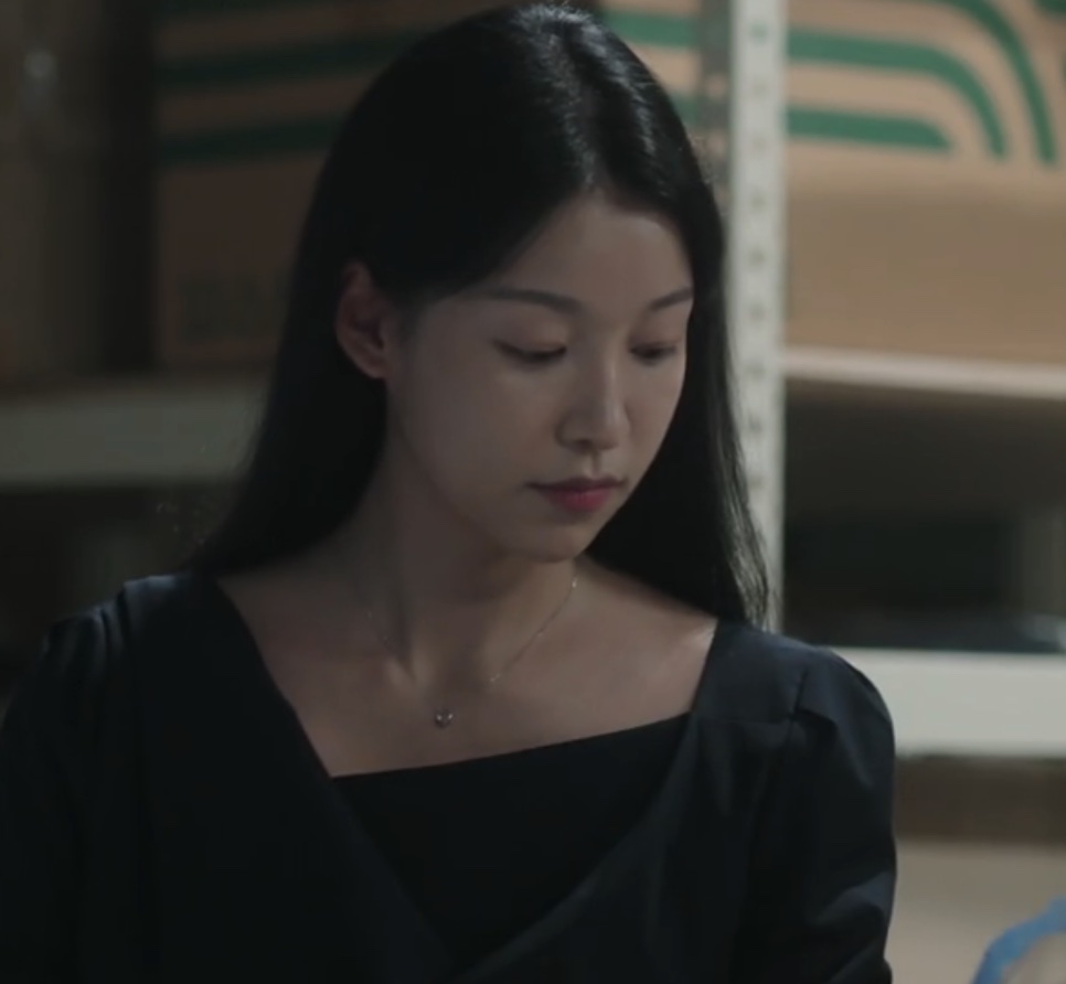 Jang Hyang-eun de roupa preta, olhando para baixo numa cena escura de The Ordinary Jackpot