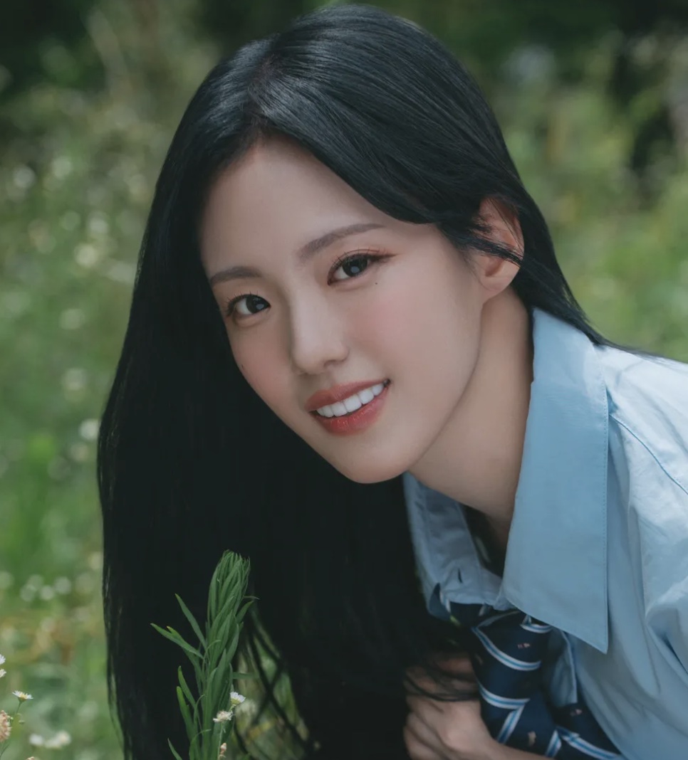 Yunseul, do grupo BEWAVE e ex-integrante do OAHSIS, sorrindo de camisa azul no meio das plantas