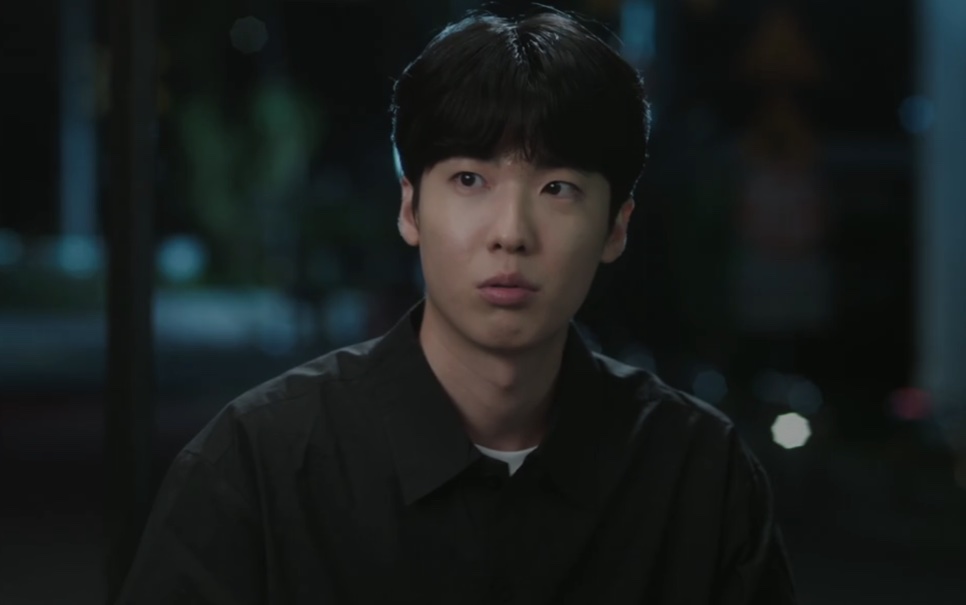 Park Ki-tae, de camisa preta, olhando para alguém numa cena à noite em The Ordinary Jackpot