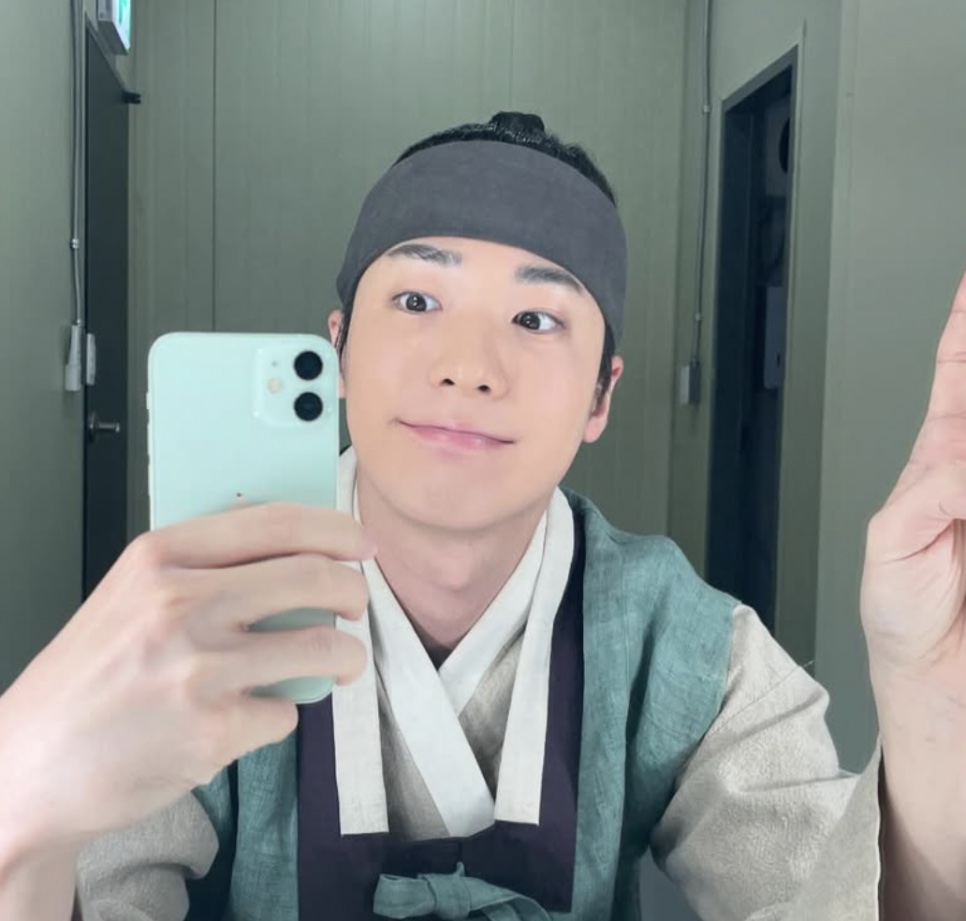 O ator Hong Jin-gi com figurino de época, tirando selfie no espelho