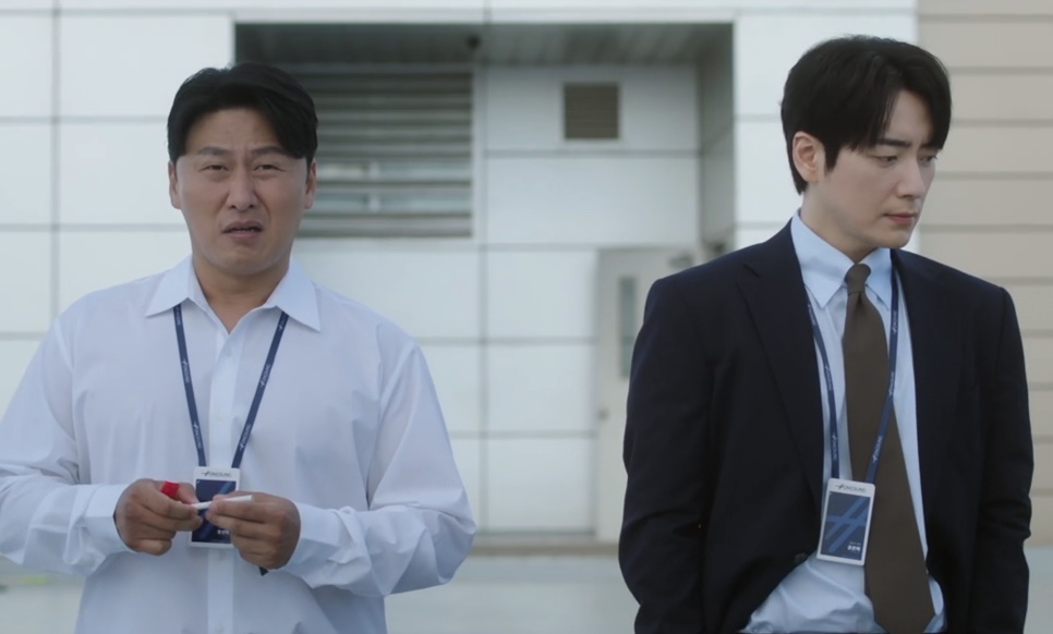 Jung Seon-hyuk, de camisa branca, ao lado do Gong Eun-tae, de terno, na frente do prédio da empresa em The Ordinary Jackpot