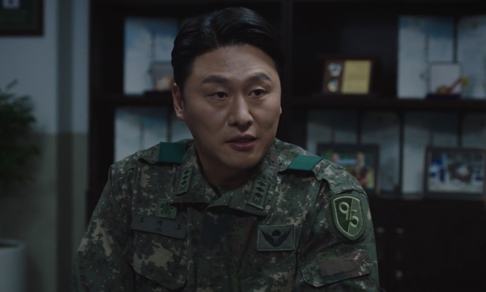 Oh Dae-hwan de uniforme camuflado numa sala do quartel, no papel do comandante Jo Baek-ho em New Recruit 4
