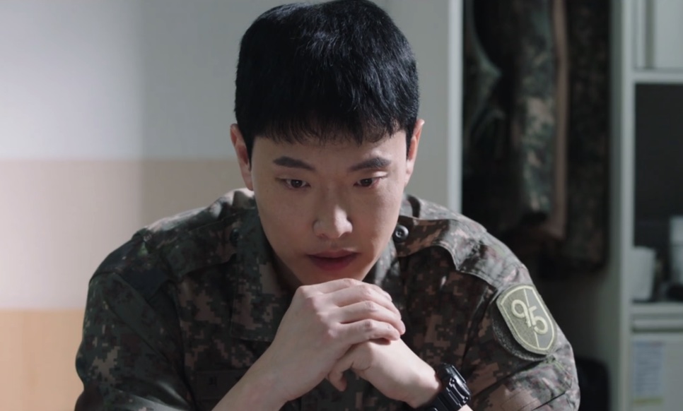 Um soldado jovem de uniforme camuflado, com as mãos cruzadas, numa cena de New Recruit 4