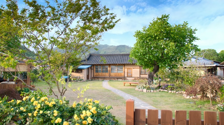 Casa hanok de dia, com flores amarelas no jardim
