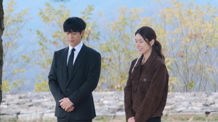 Tae-ha de terno preto ao lado de Eun-sae, junto à muralha
