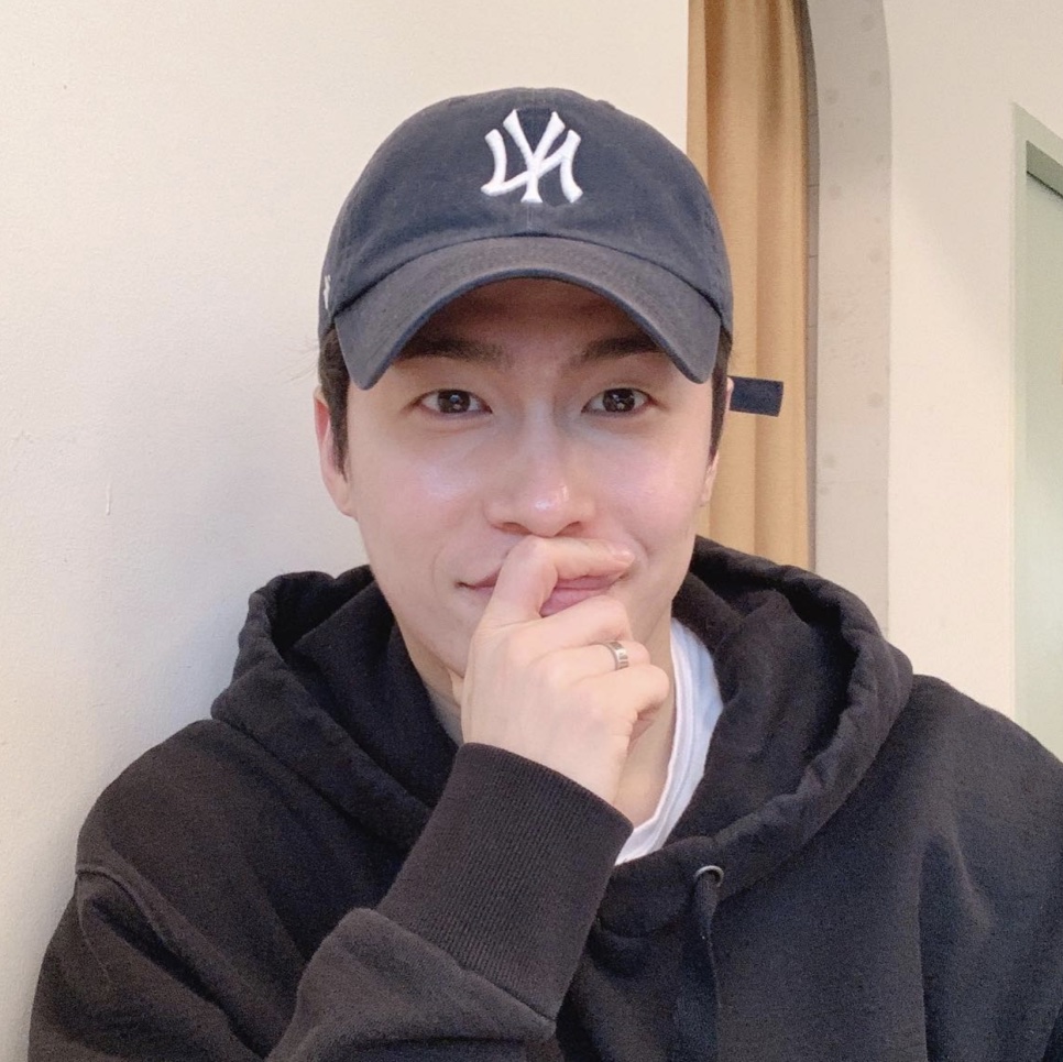 Lee Jae-won de boné e moletom, sorrindo em outra selfie