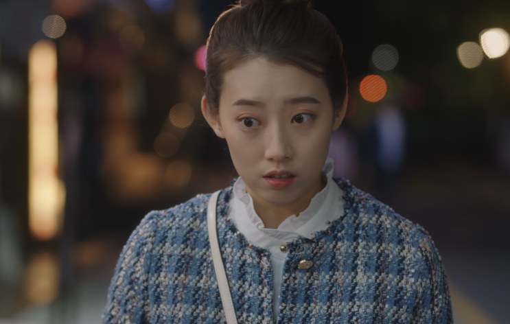 Shin Hye-young de casaco de tweed azul, parada na rua à noite