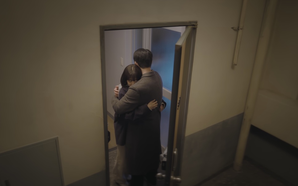 O Ho-su e a Mi-ji abraçados na porta de entrada, vistos de longe