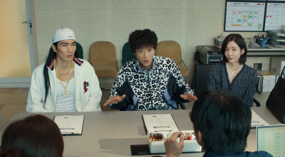 Gu Sang-gu de boné branco e Hwang Hyun-woo de jaqueta de oncinha sentados a uma mesa, conversando com Byeon Do-mi, em Wild Sing