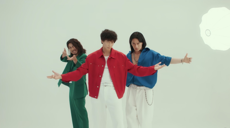 Os três integrantes do Triangle fazendo pose de grupo, de terno colorido, em Wild Sing