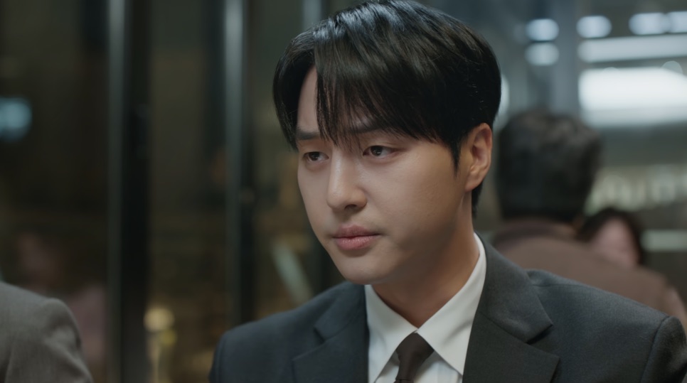 Yang Se-jong hoje, de terno cinza, rosto mais cheio e traço mais duro, olhando de lado