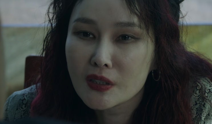 Jo Mi-yeon de perfil, olhando para baixo em um ambiente escuro