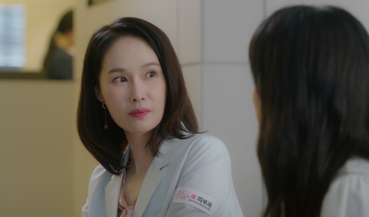 Baek Mi-hee de jaleco branco, conversando com outra pessoa no hospital