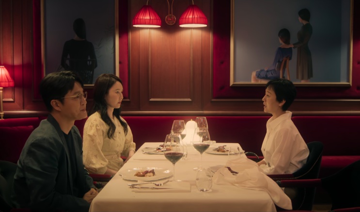 Mesa de restaurante vista de longe, com um casal jantando sob luminárias vermelhas