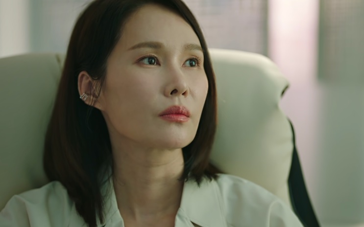 Yoon Tae-hee sentada na cadeira de uma sala de diretoria, olhando para o lado