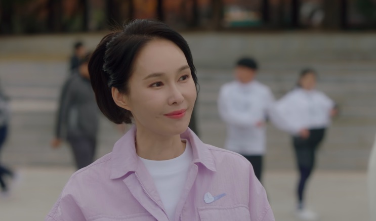 Baek Mi-hee de jaqueta rosa, caminhando em uma área externa