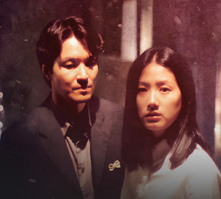 Han Suk-kyu e Shim Eun-ha lado a lado em cena do filme, com expressão séria